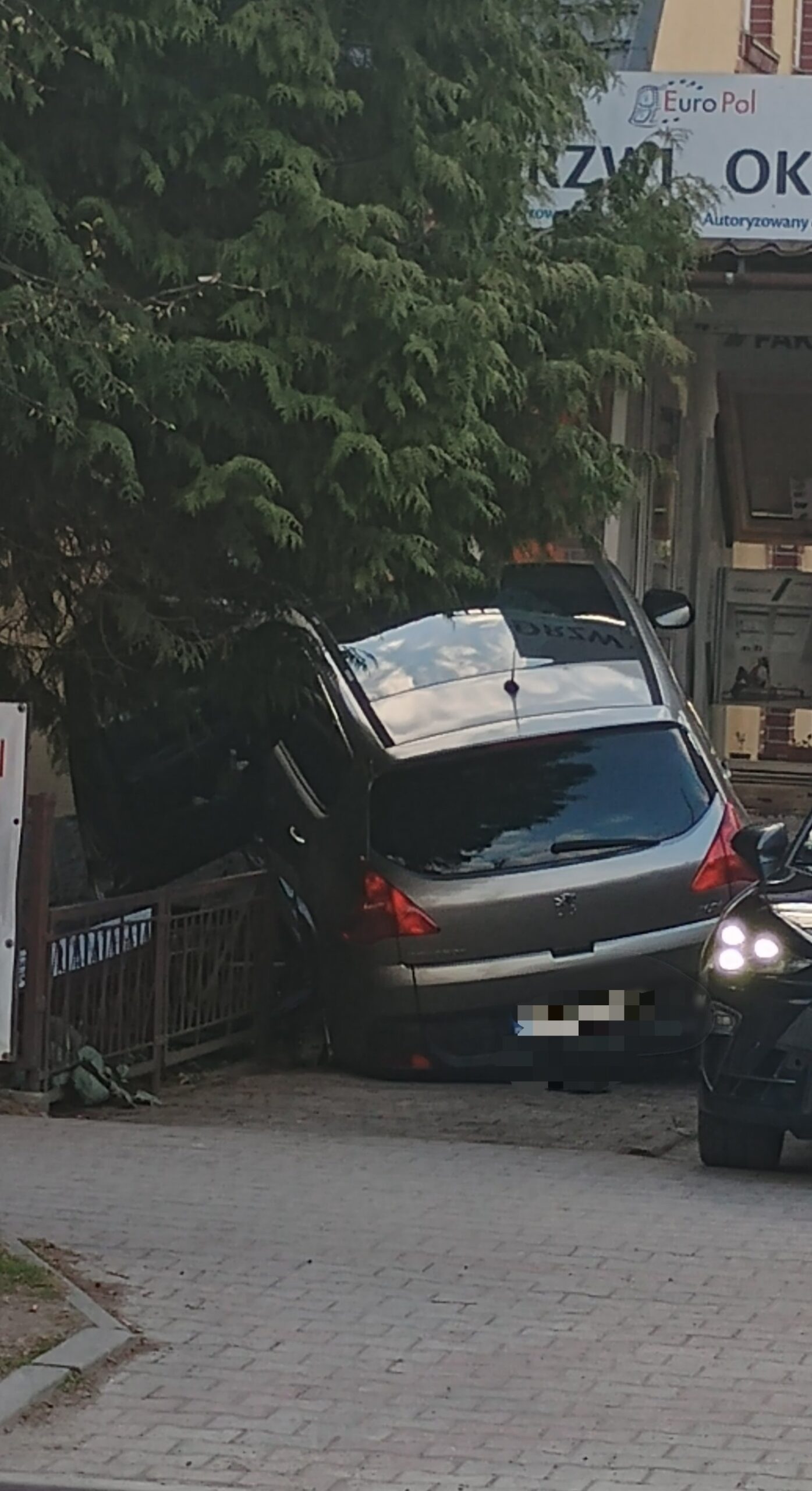 Srebrny samochód Peugeot zaparkowany na schodach przed sklepem z oknami w Kudowie-Zdroju po wypadku drogowym