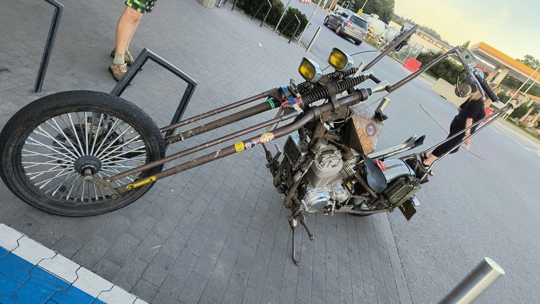 Customowy motocykl w stylu postapokaliptycznym z bardzo długim przednim widelcem i rdzawym wykończeniem